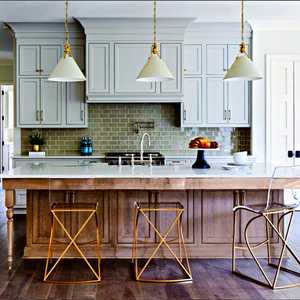 Luxury kitchen with light bluish-gray, shaker-style cabinets beyond a large kitchen island that accommodates seating and sports a white countertop marbled to match the cabinets
